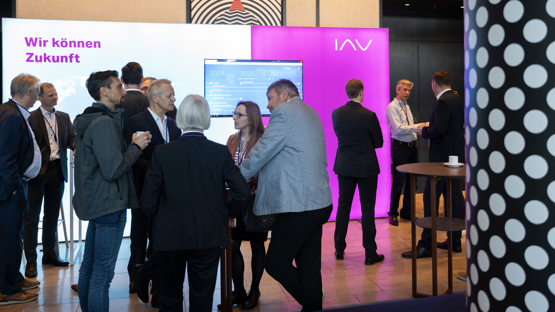 Several groups of people in the exhibition area surrounded by stands and exhibits.