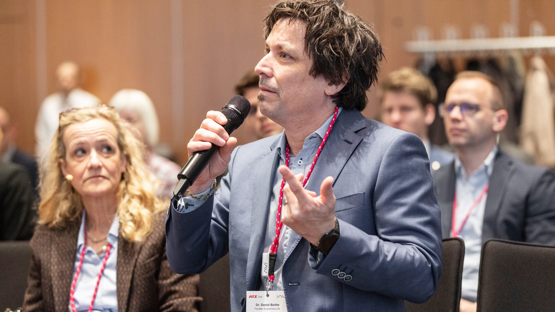 Question from the audience. Man with microphone sitting, surrounded by plenum.