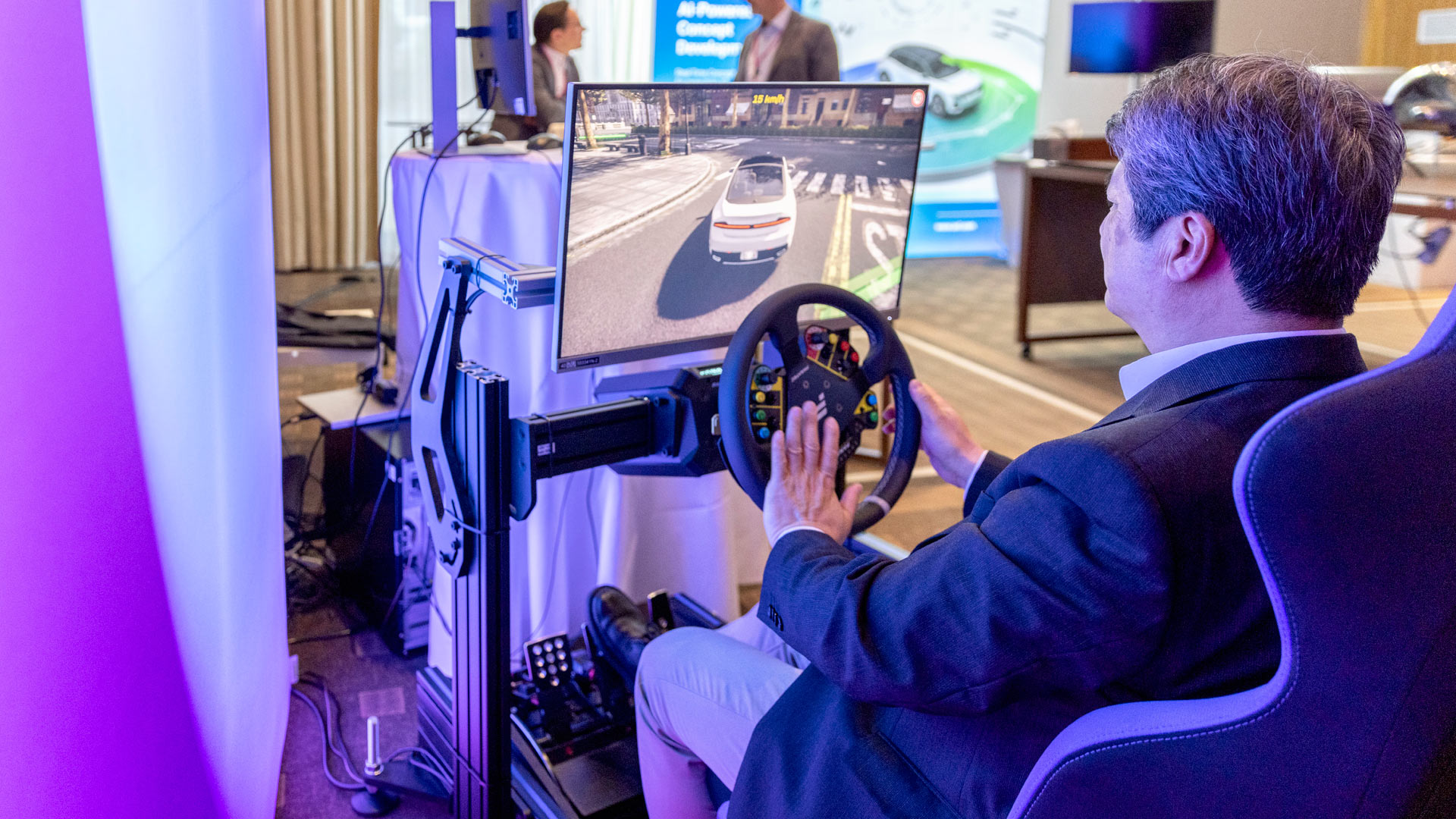 Man sitting in a driving simulator in the exhibition area of the conference.
