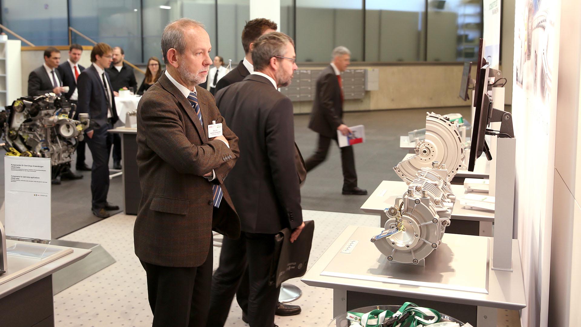 Several gentlemen look at exhibits in the exhibition area.