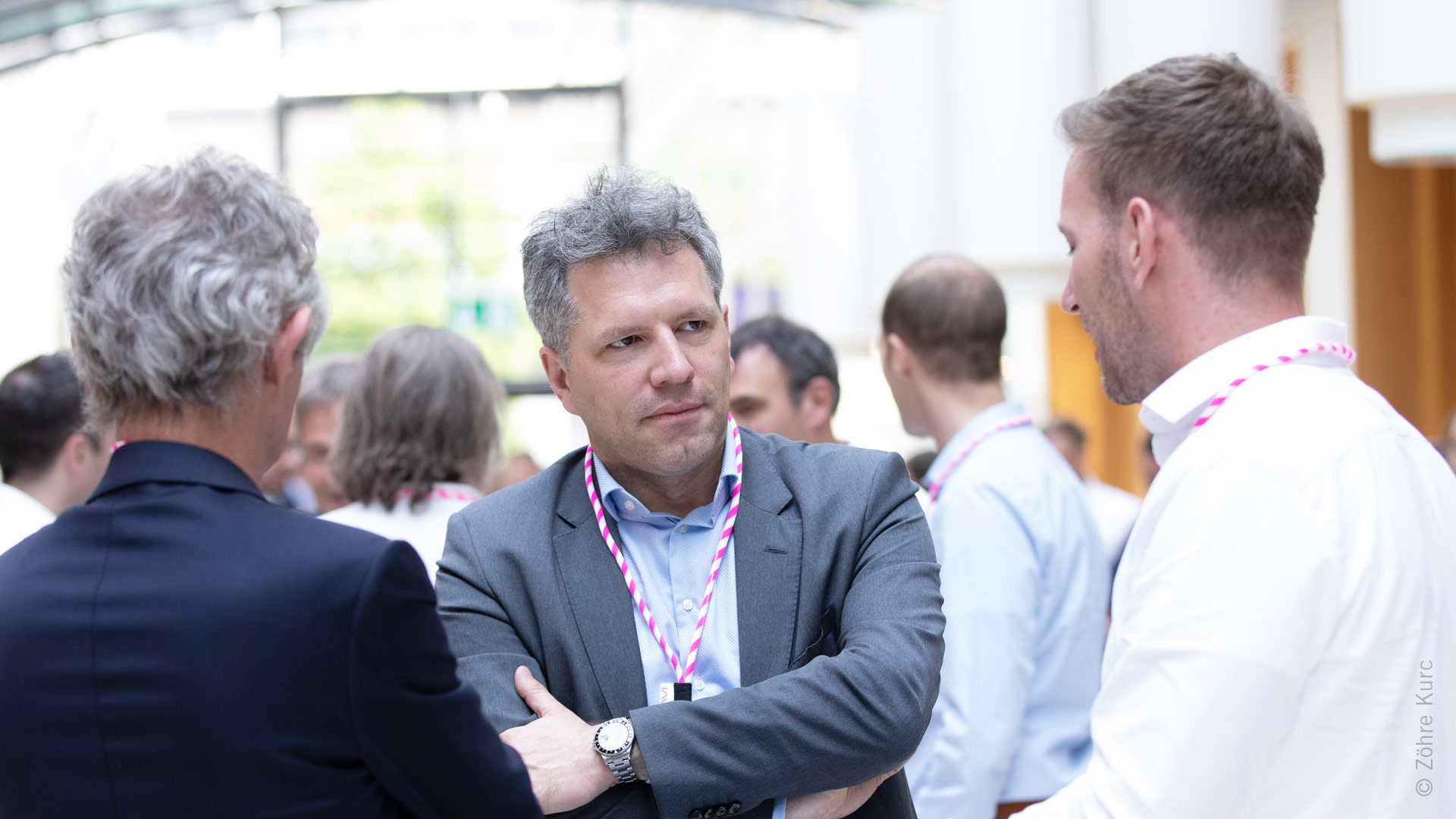 Mehrere Gruppen von Menschen im Ausstellungsbereich umgeben von Ständen und Exponaten.