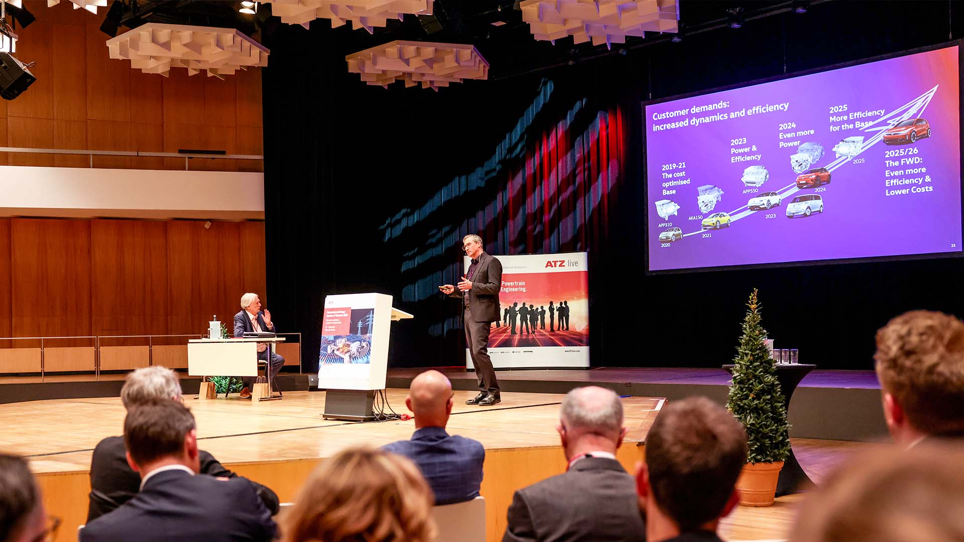 Speaker on stage during his presentation. The audience in the forefront