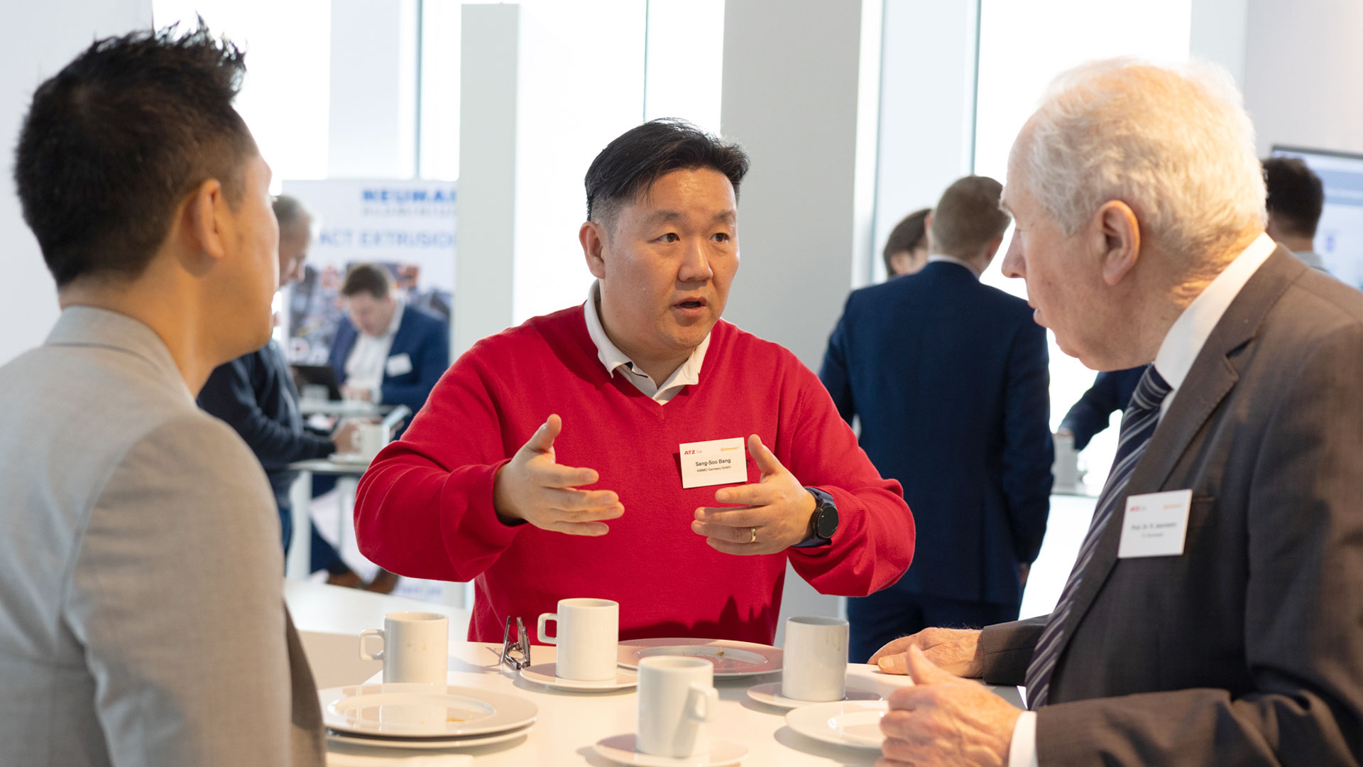 Drei Konferenzteilnehmer während der Kaffeepause im Gespräch am Stehtisch. 