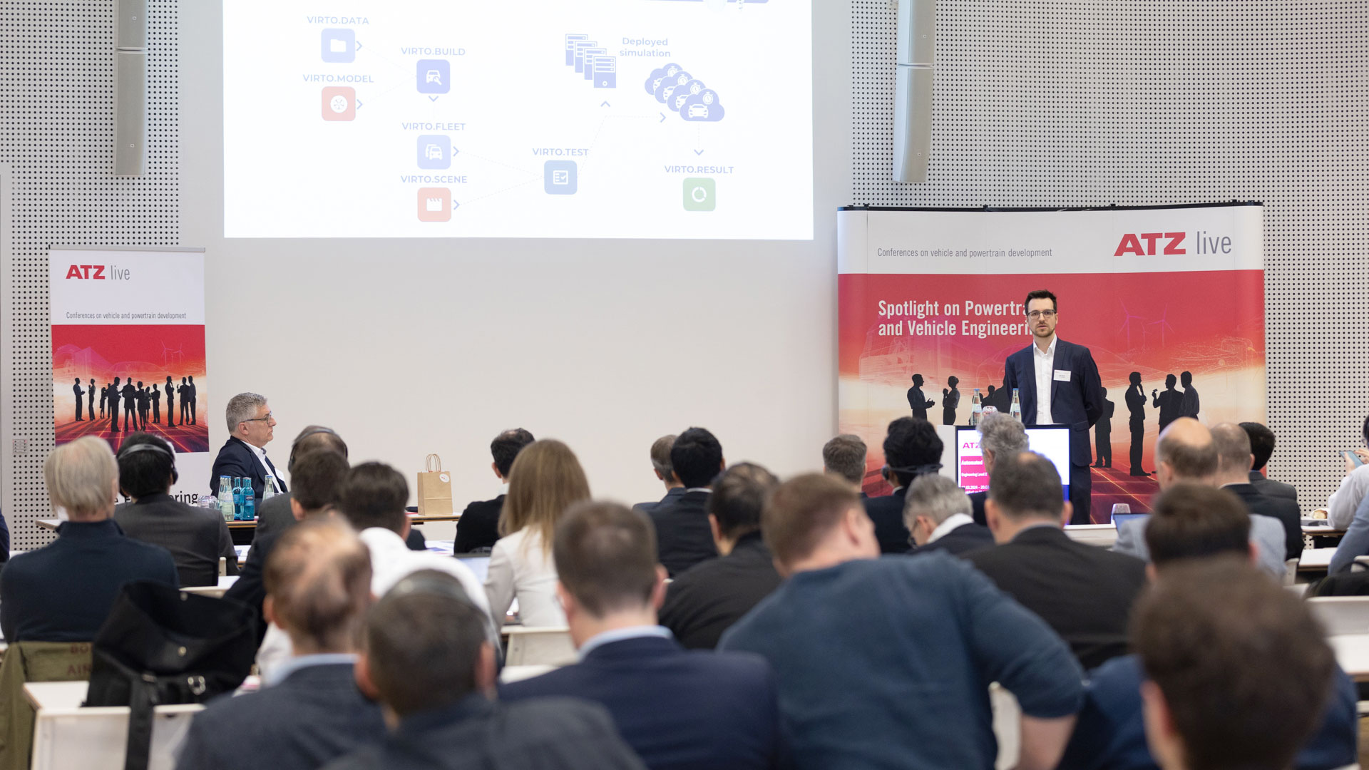 Speaker on stage during his presentation. The audience in the forefront