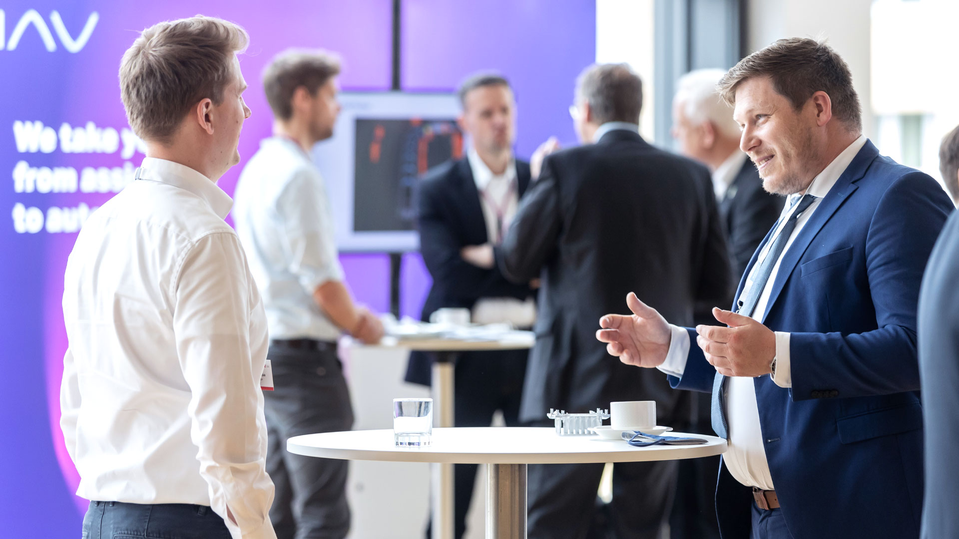 Konferenzteilnehmer während der Kaffeepause im Gespräch am Stehtisch. 