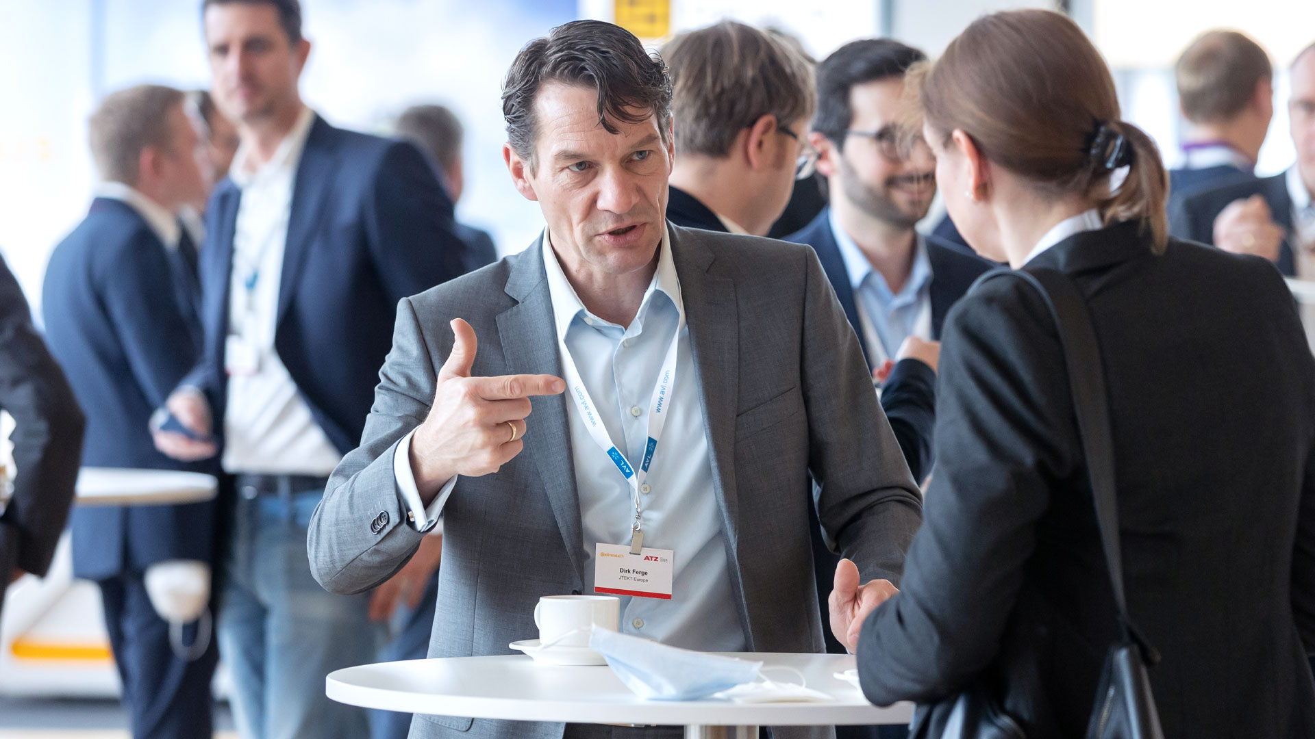 Konferenzteilnehmer während der Kaffeepause an Stehtischen im Gespräch. 