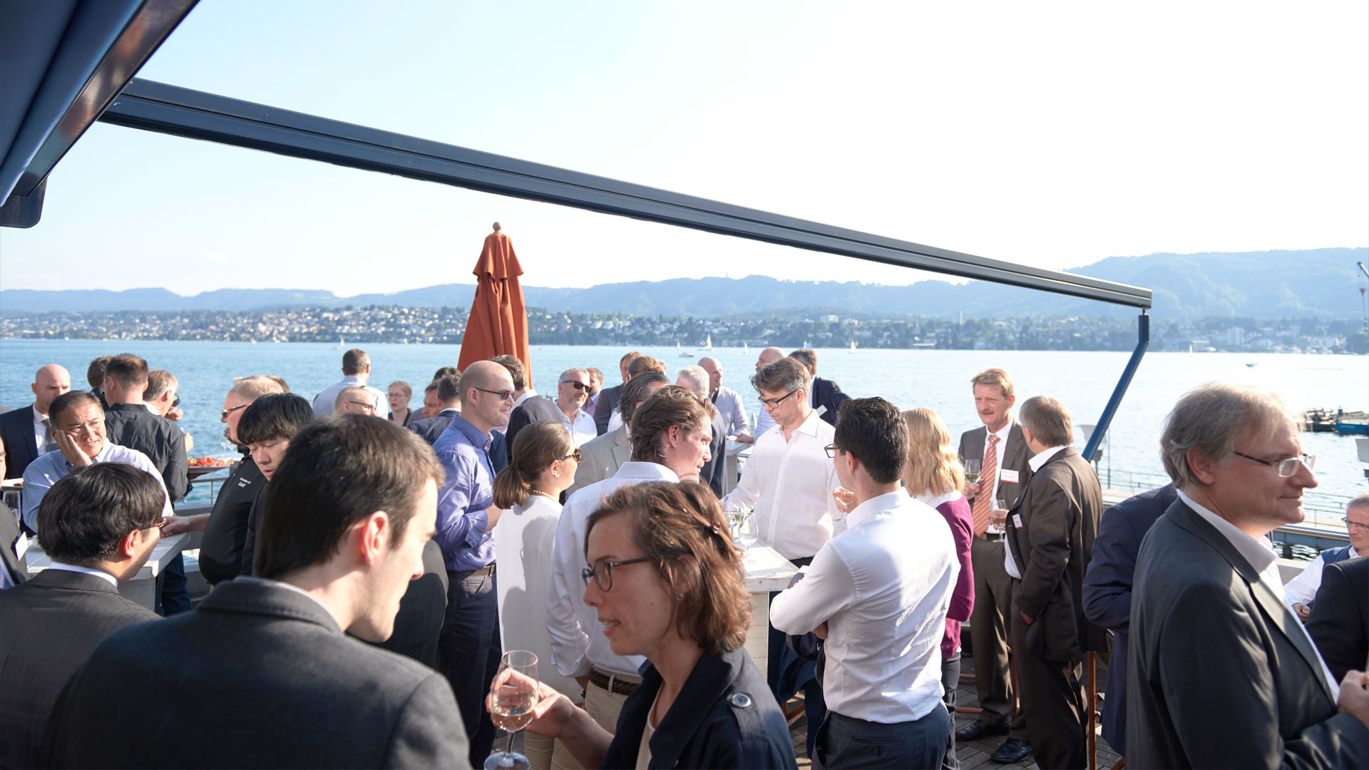 Gruppen von Konferenzteilnehmern im Gespräch am Ufer des Zürich Sees. 