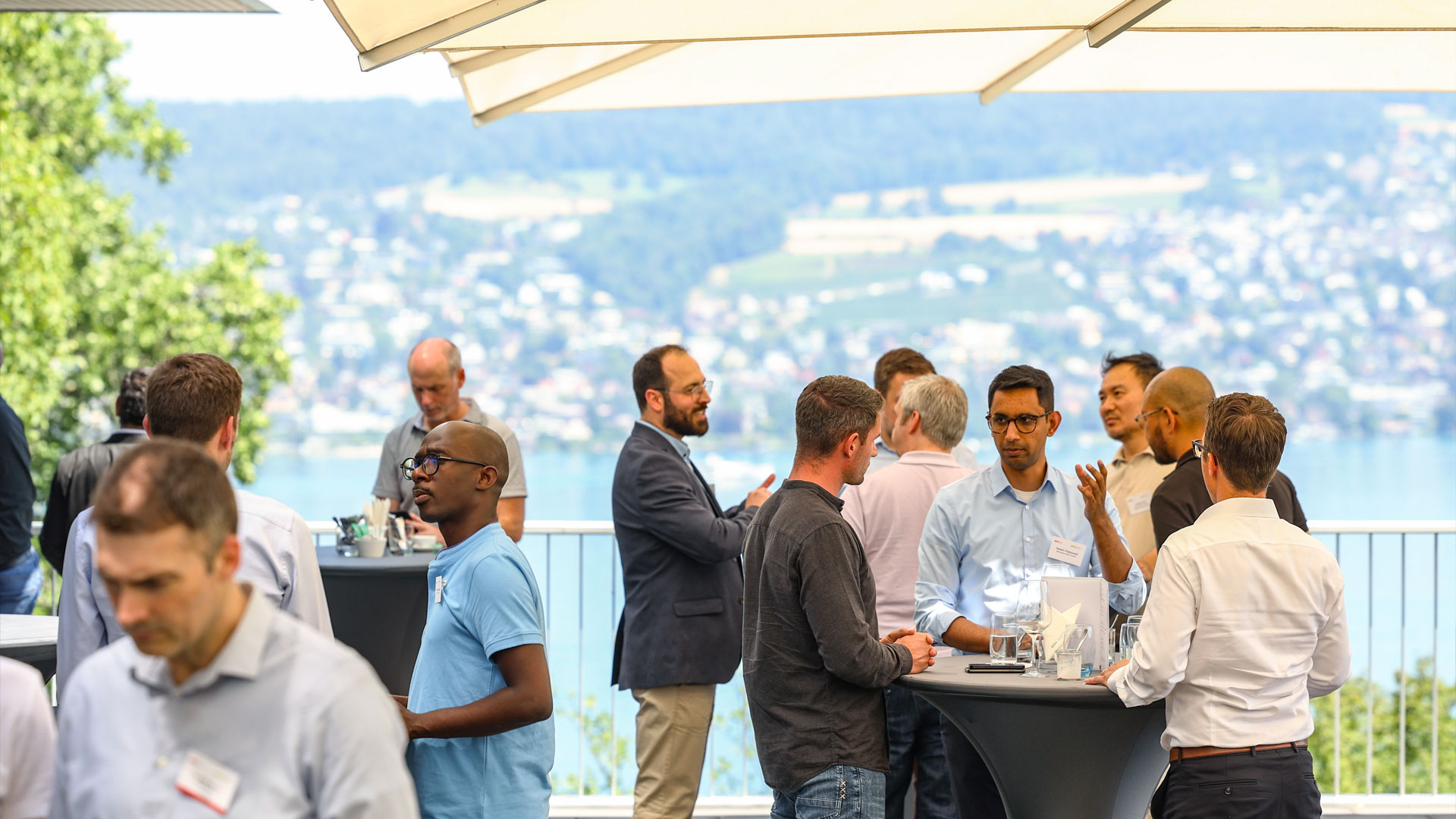 Konferenzteilnehmer im Gespräch in der Pause im Freien mit Blick auf den Zürich See. 
