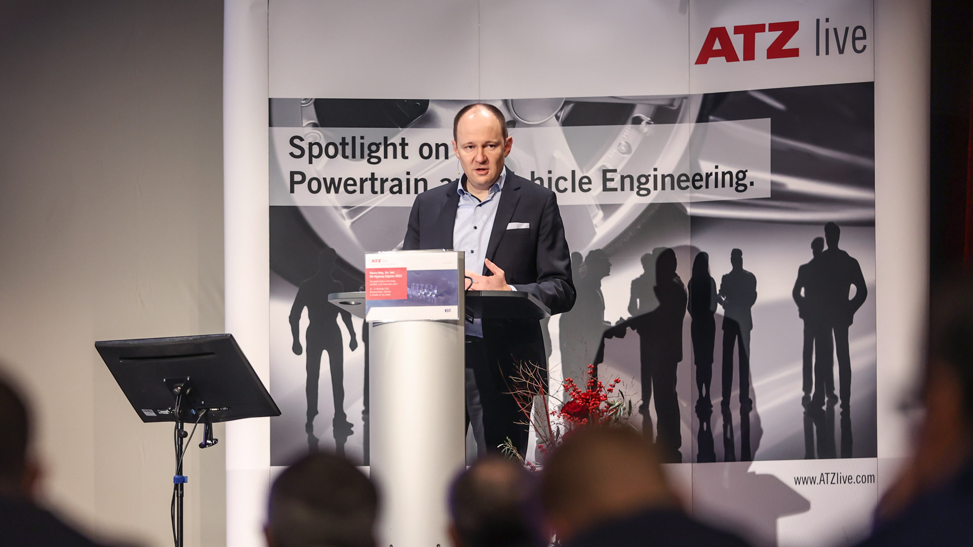 Speaker on stage during his presentation. The audience in the forefront