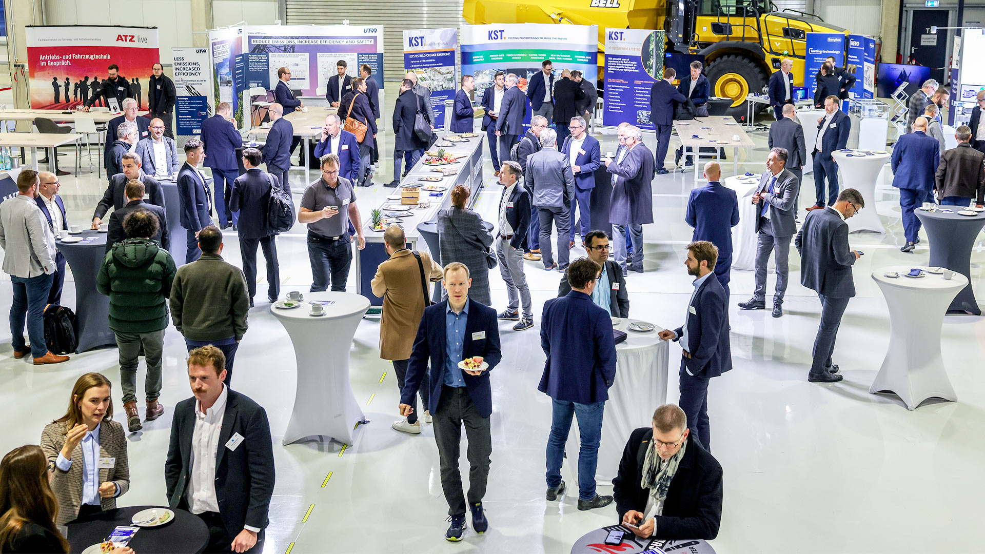 Several groups of people in the exhibition area surrounded by stands and exhibits.