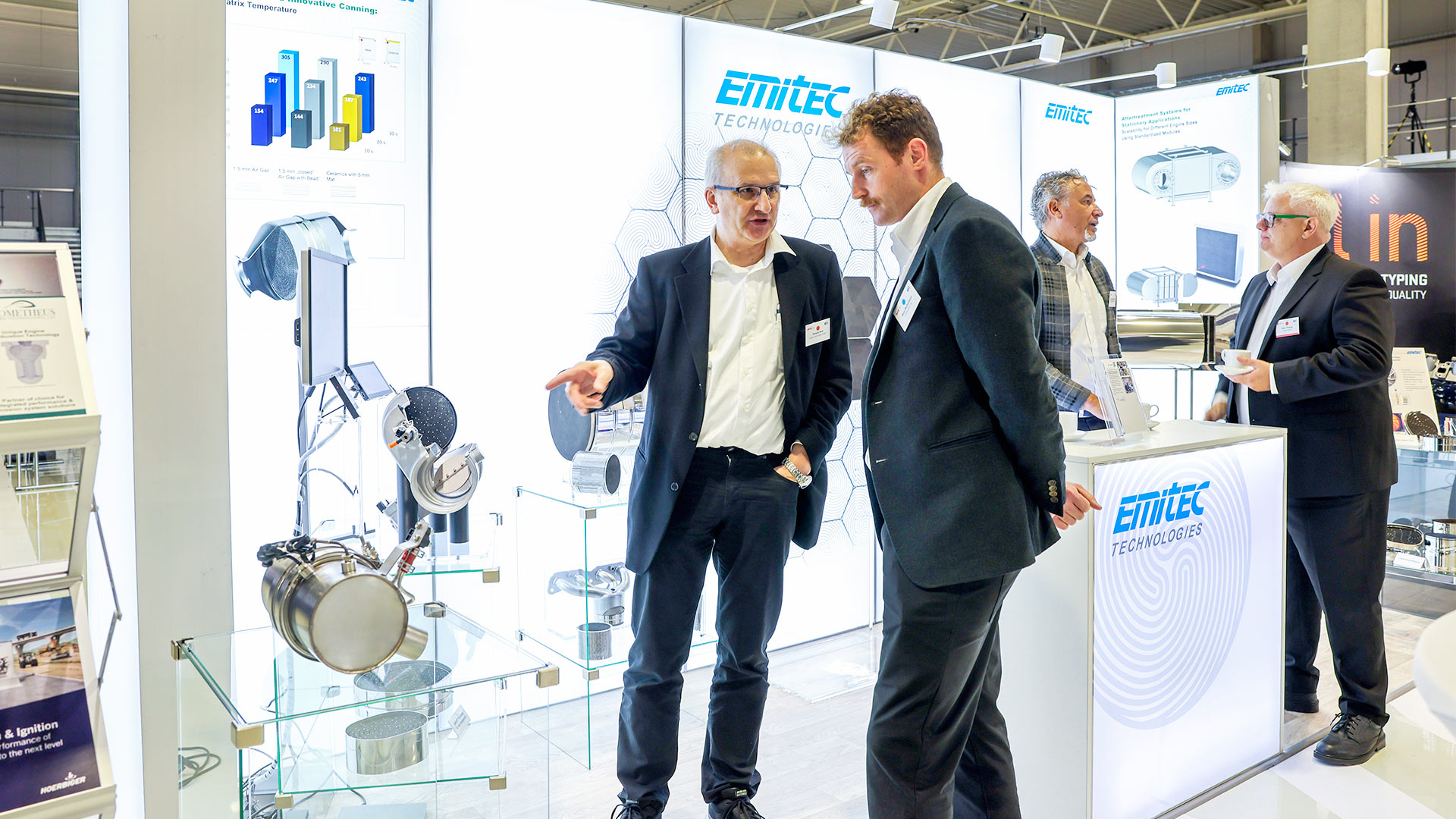 Two groups in conversation at the Emitec exhibition stand.