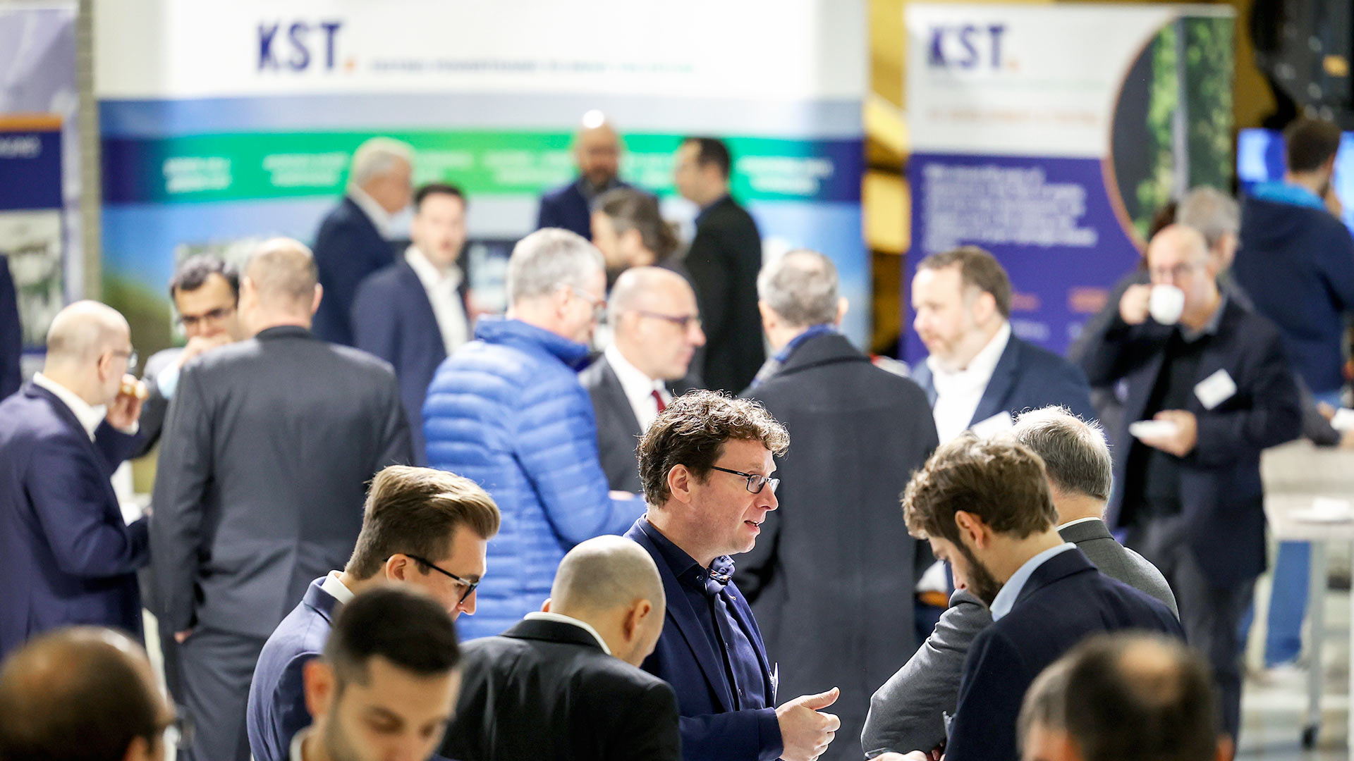 Several groups of people in the exhibition area surrounded by stands and exhibits.