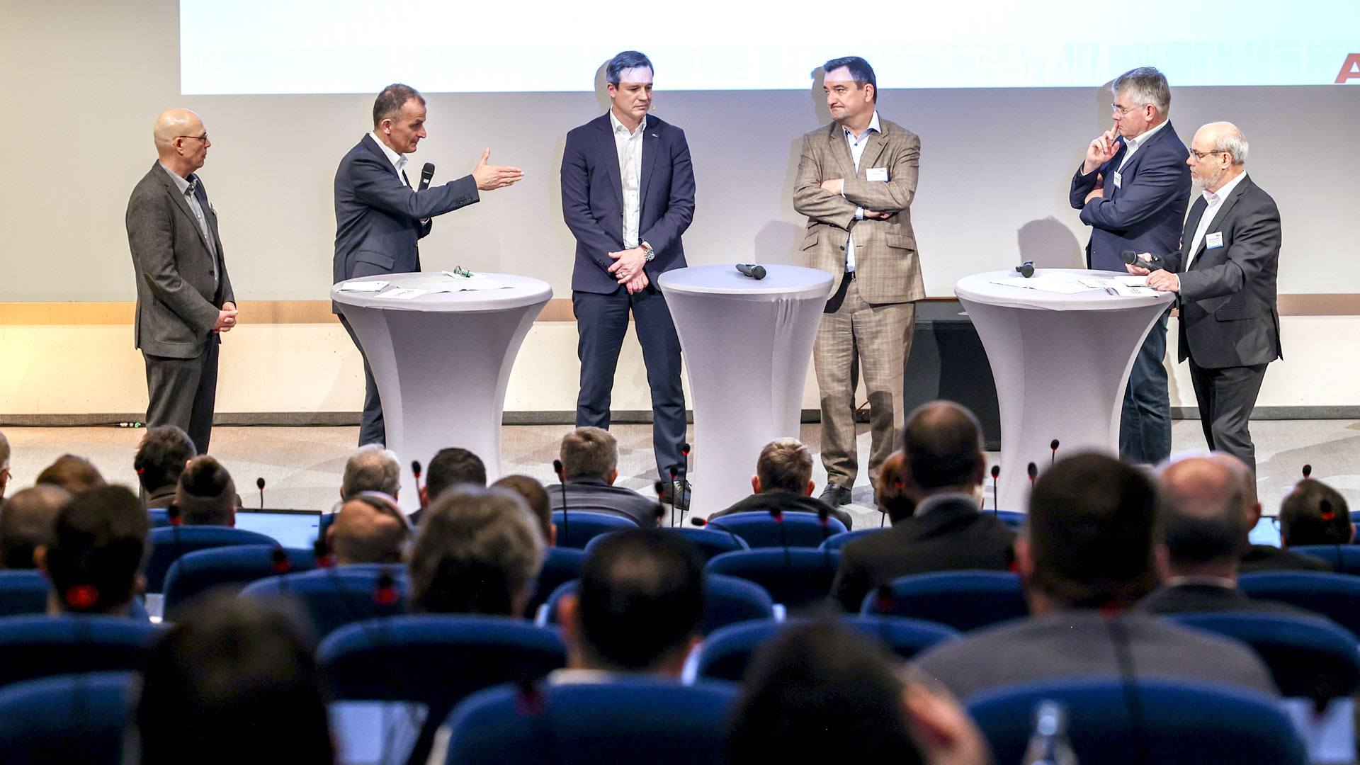 Sechs Konferenzbeteiligte einer Podiumsdiskussion auf der Bühne