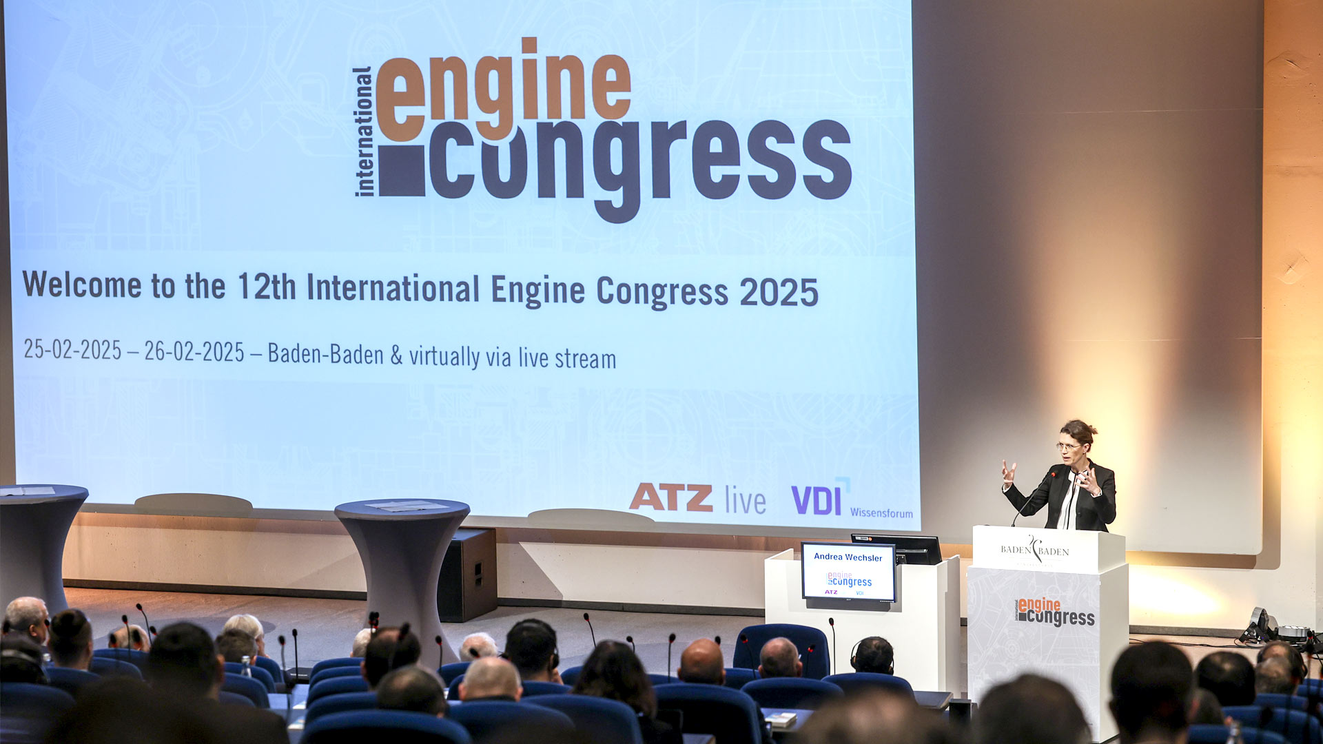 Speaker on stage during his presentation. The audience in the forefront