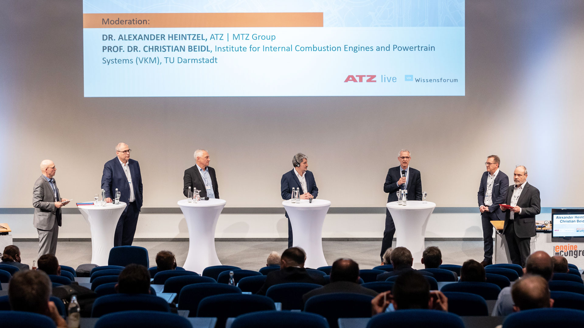 Podiumsdiskussion mit sieben Konferenzbeteiligten auf Bühne vor Publikum