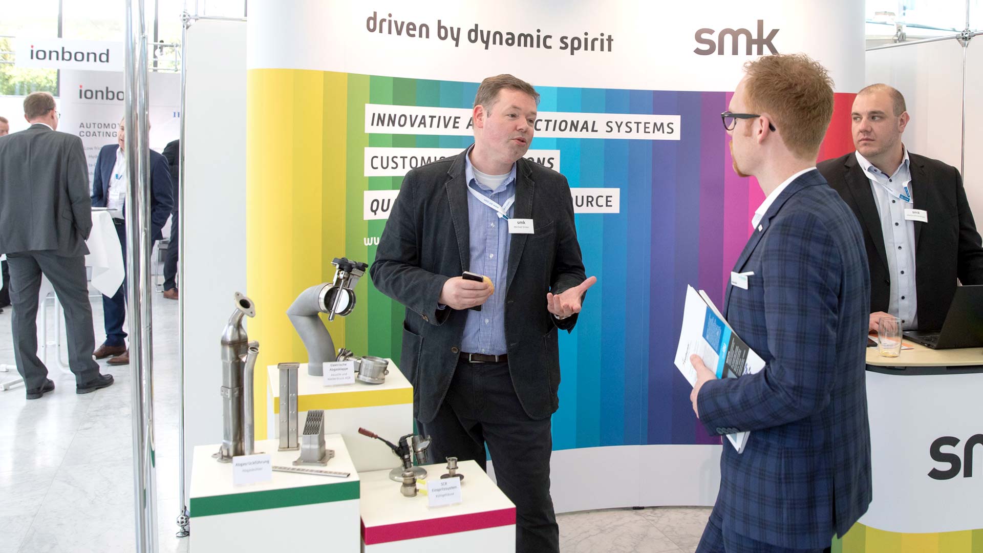 Two gentlemen in conversation at the smk exhibition stand.