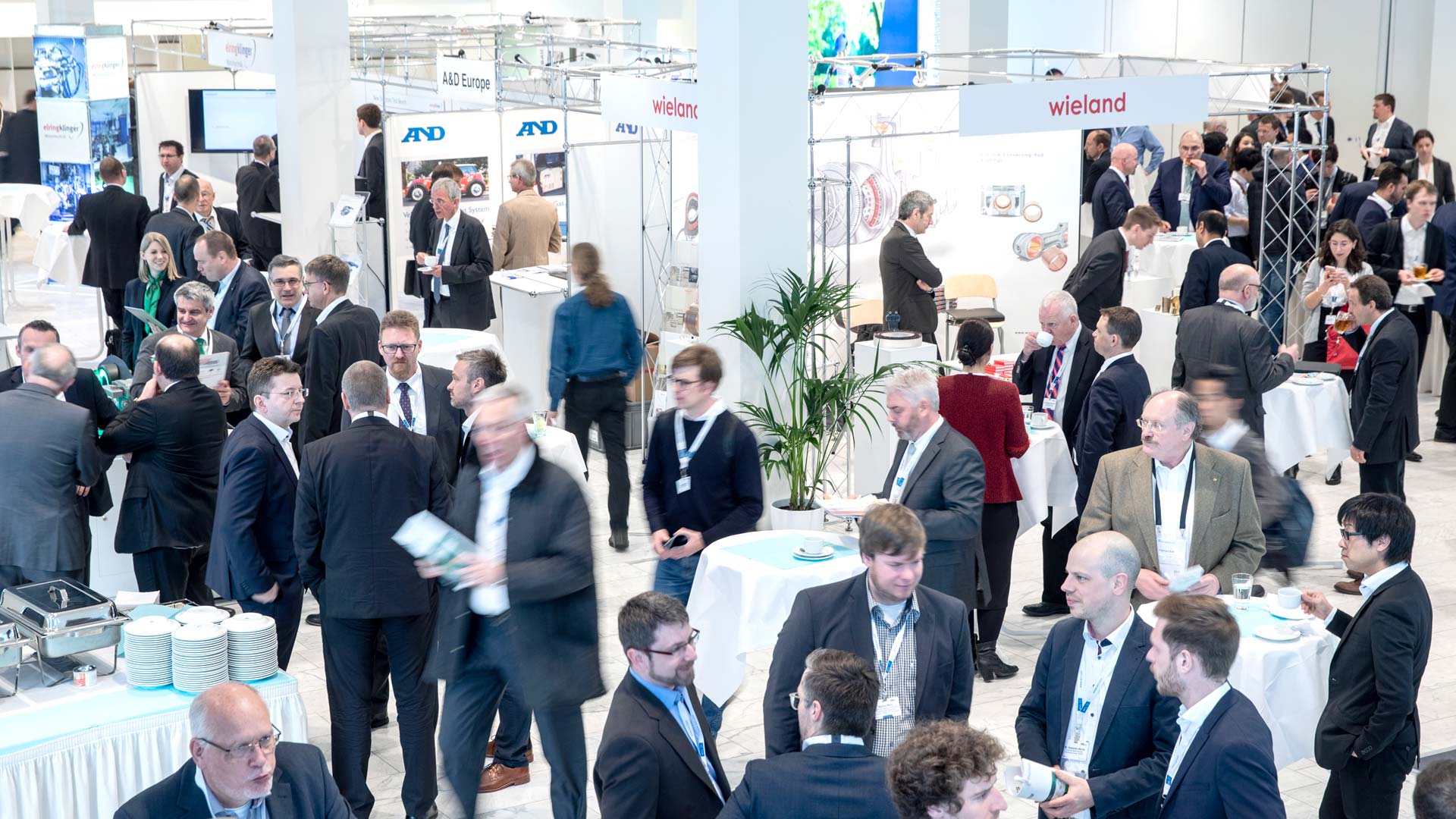 Several groups of people in the exhibition area surrounded by stands and exhibits.