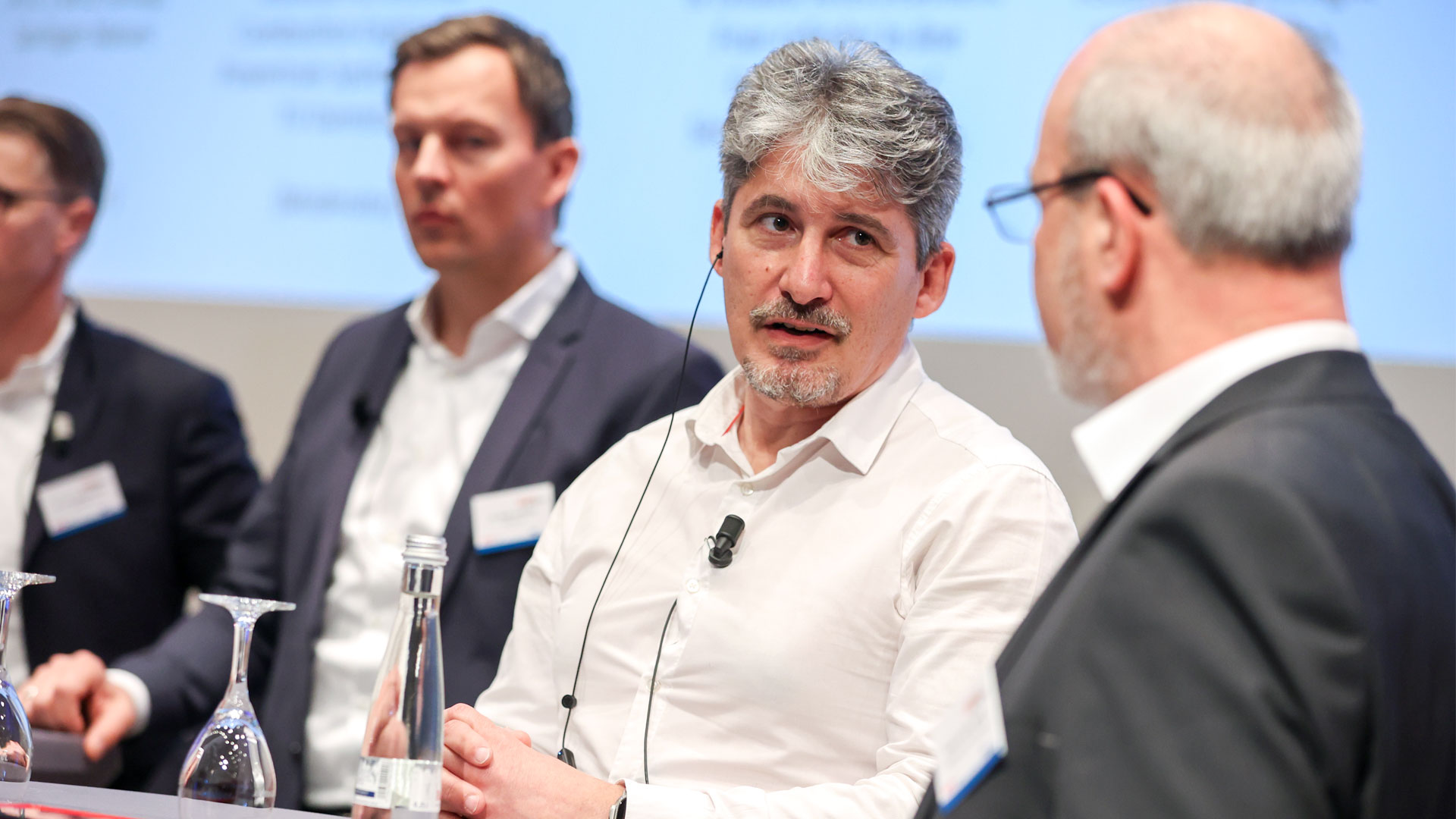 Vier Konferenzbeteiligte einer Podiumsdiskussion auf der Bühne