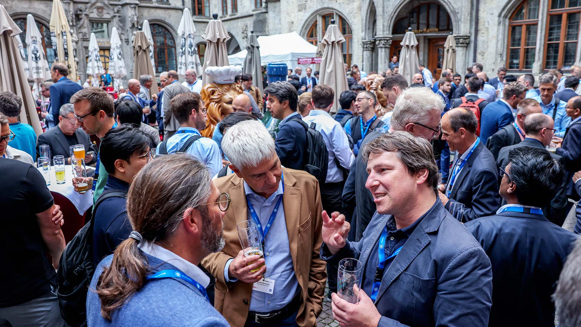 Konferenzteilnehmer unterhalten sich beim Networking-Abendevent im Freien. 