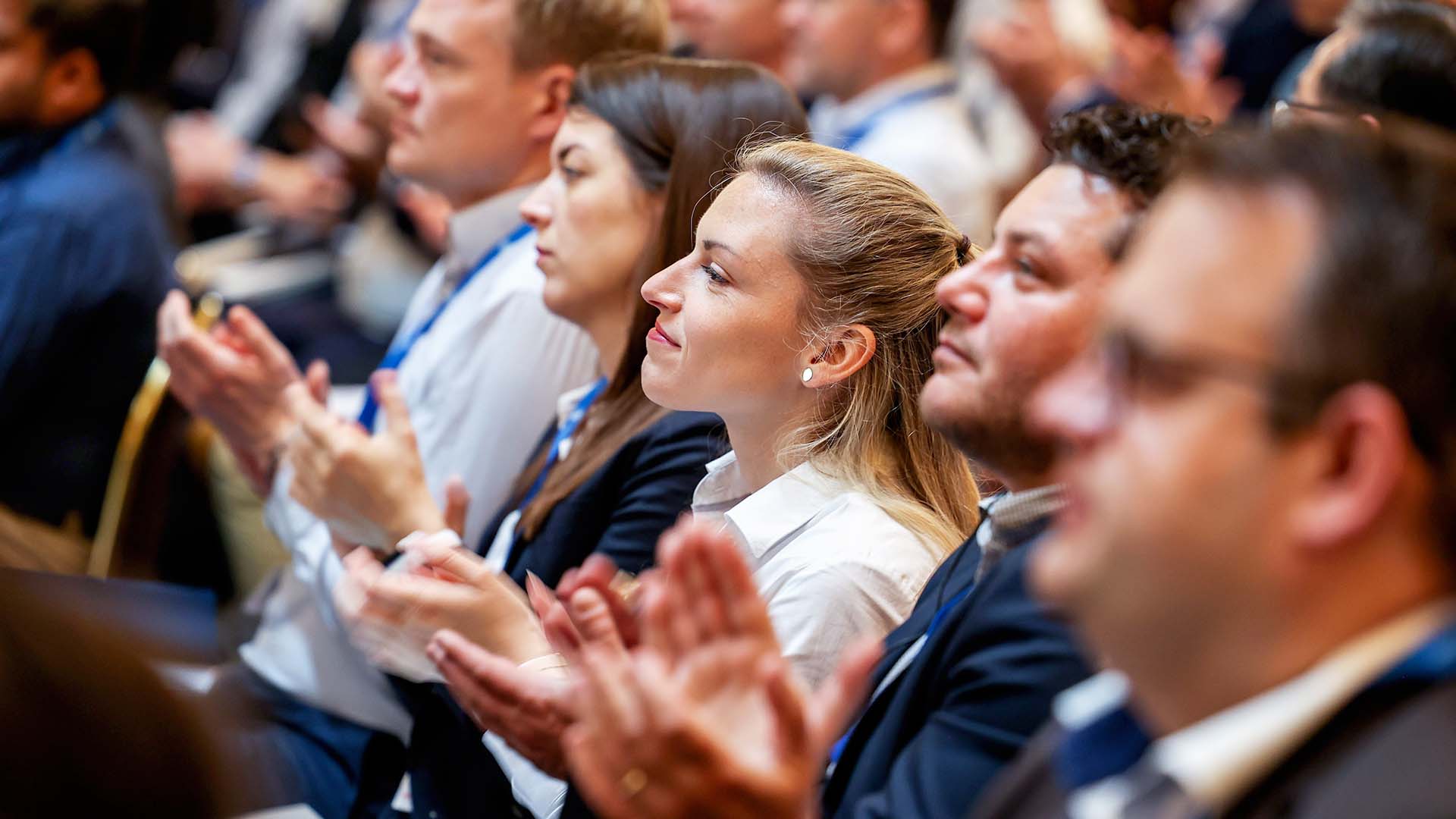 Klatschende Konferenzteilnehmer sitzend im Plenum 