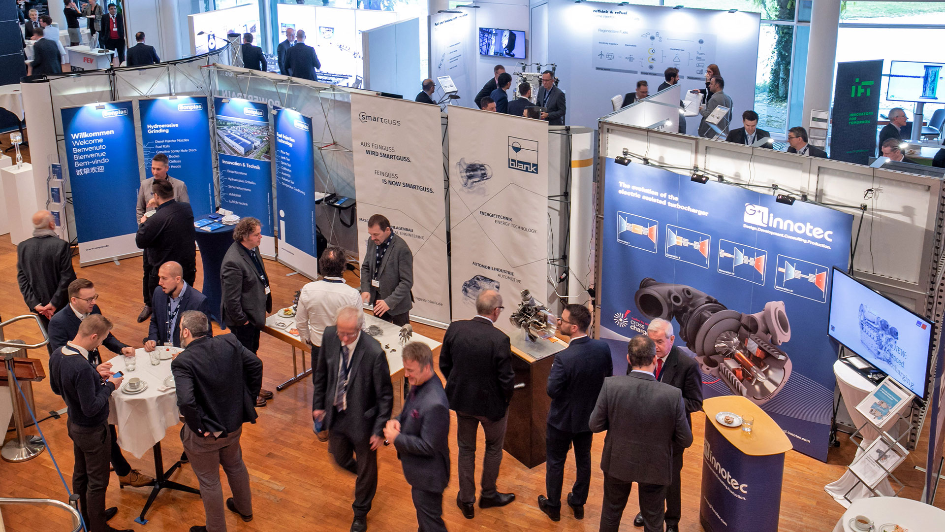 Groups of conference participants chat in the exhibition area.