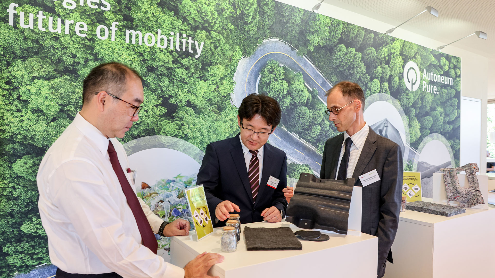 Three gentlemen in conversation at the exhibition stand of Autoneum.